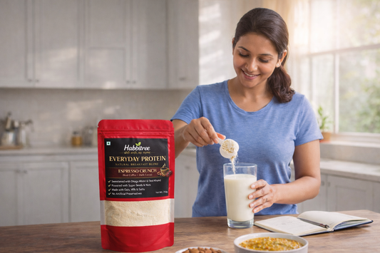 **Alt text:**  Busy Indian woman preparing a daily protein shake in a home kitchen with Habbitree Everyday Protein pouch on the counter, showing a simple everyday nutrition habit for women.